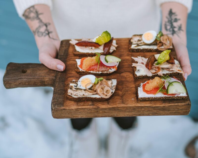 Person in winter sweater holding a tray of festive open-faced sandwiches.